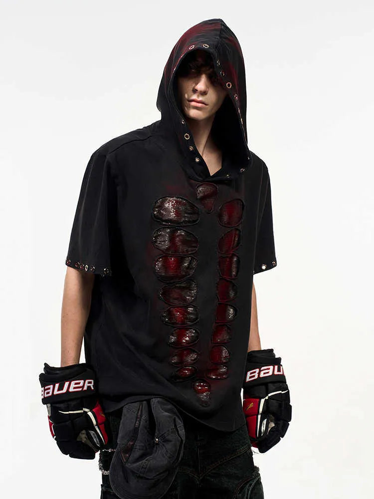 Man wearing a black hooded T-shirt covered in sequins, showing loose fit and short sleeves.