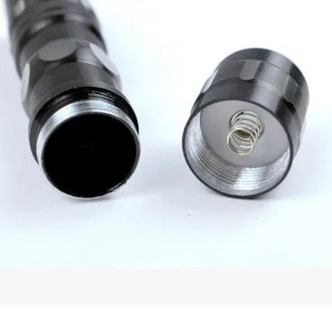 Black aluminium mini LED flashlight showing size next to a AA battery for scale.