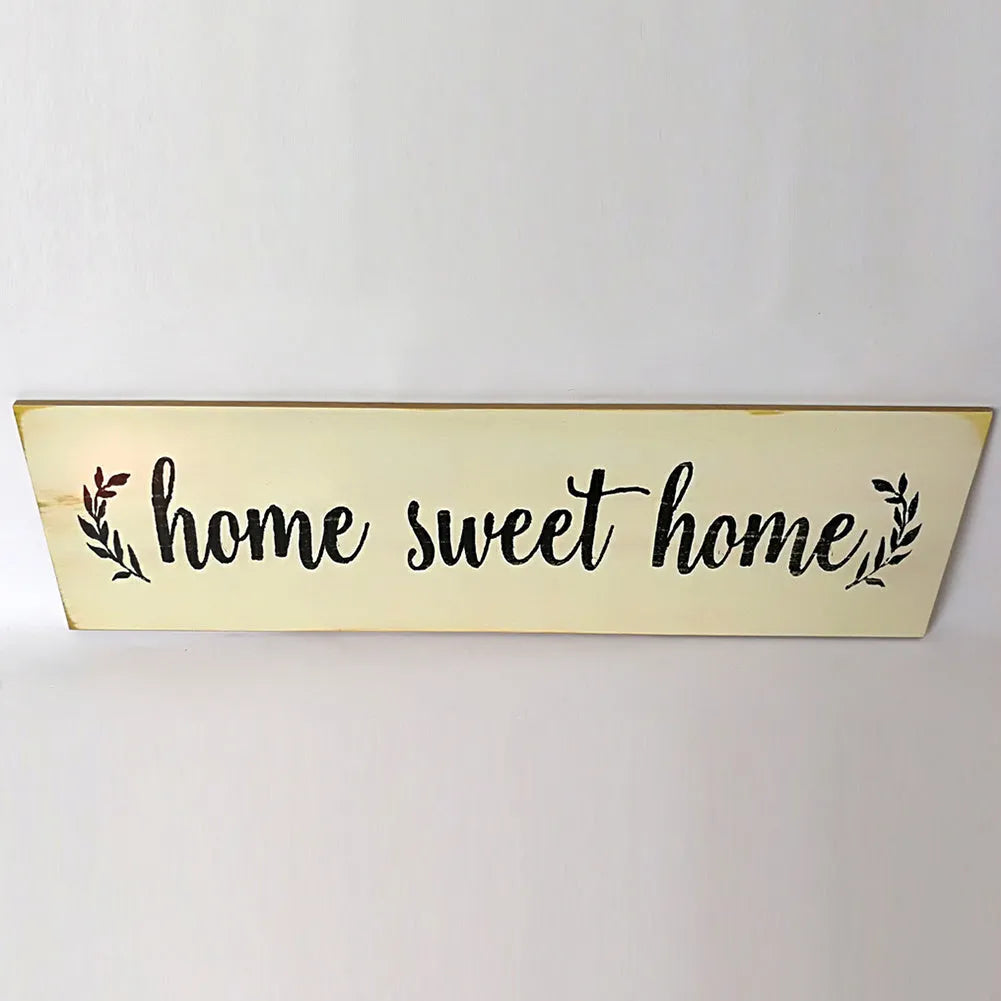 Wooden carved Home Sweet Home wall hanging ornament in black, 40cm long, 12cm high, on a white wall