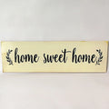 Wooden carved Home Sweet Home wall hanging ornament in black, 40cm long, 12cm high, on a white wall