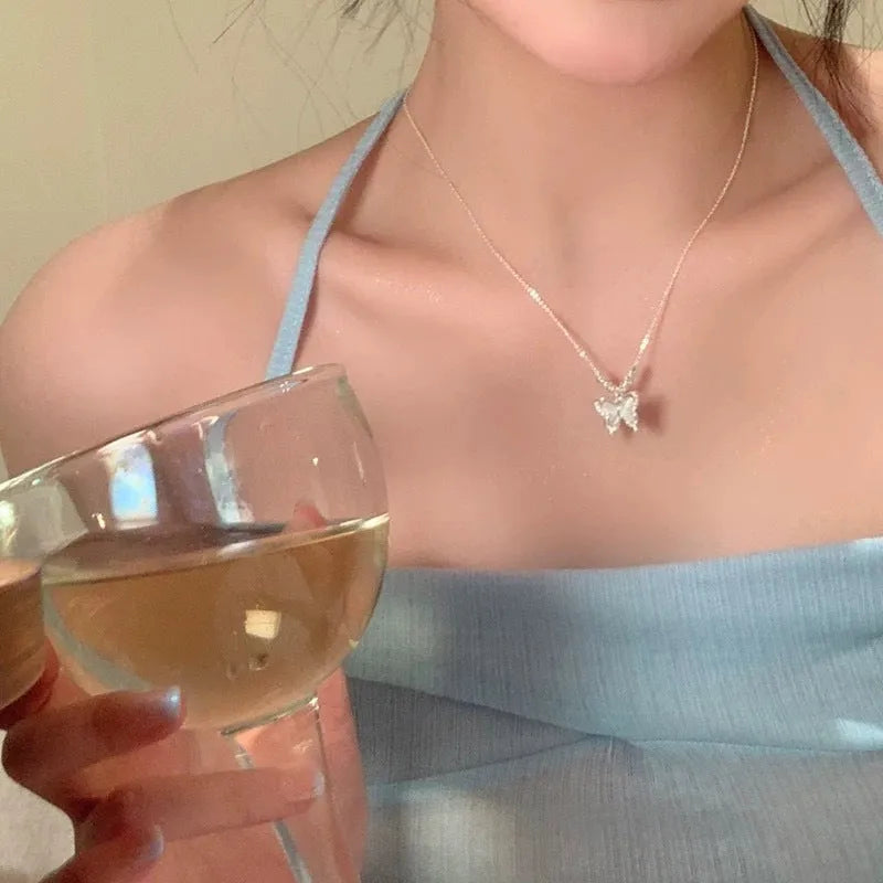 A silver necklace with a butterfly pendant on a cross chain, showing adjustable length.