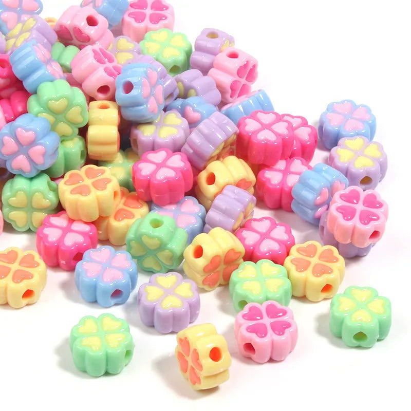 Assortment of 15mm frosted acrylic four-leaf clover craft beads in light colours.