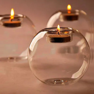 Handmade round hollow glass candle holder in three sizes on a wooden table.