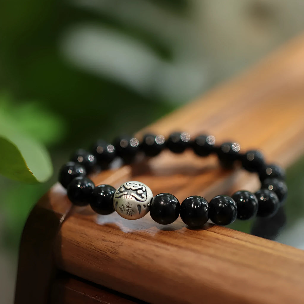 Close-up of a bracelet with large round black agate beads and sterling silver components on a wrist.
