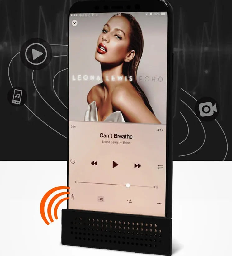Portable black ABS plastic phone amplifier holder with an iPhone inserted, shown on a desktop.