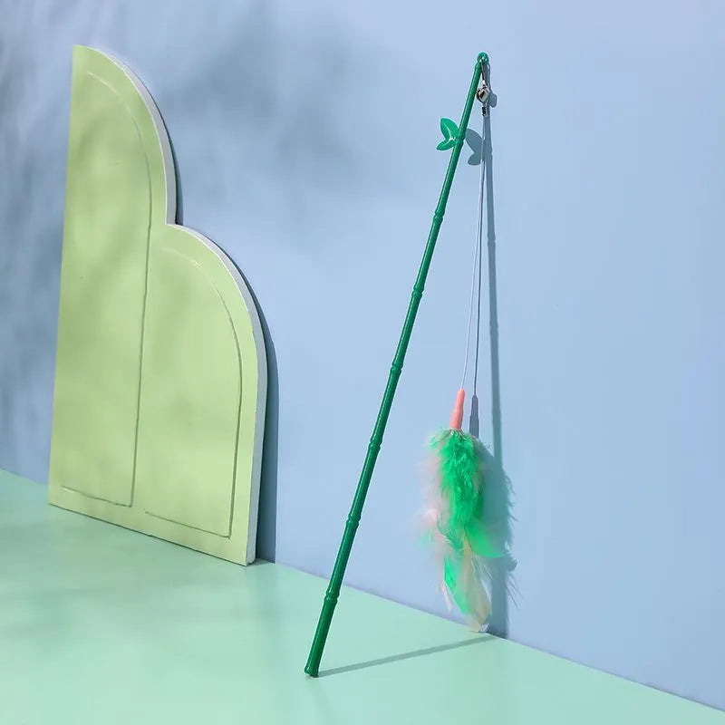 Green interactive cat feather wand toy with bells on a light background