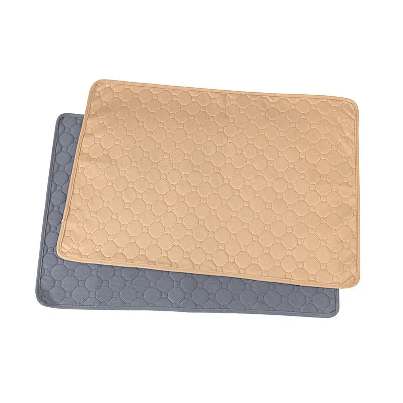 Two washable dog pee pads in grey and khaki on a floor, one with a small dog standing on it