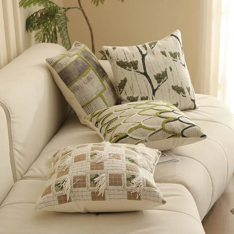 Square jacquard cushion cover with woven floral pattern on a grey sofa, showing zip closure and textured fabric.