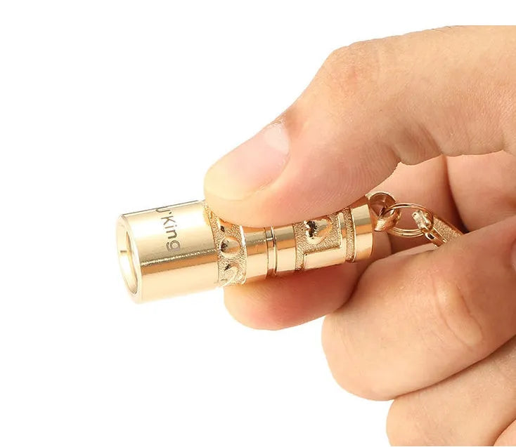 Gold-coloured waterproof mini LED flashlight on a keychain ring.