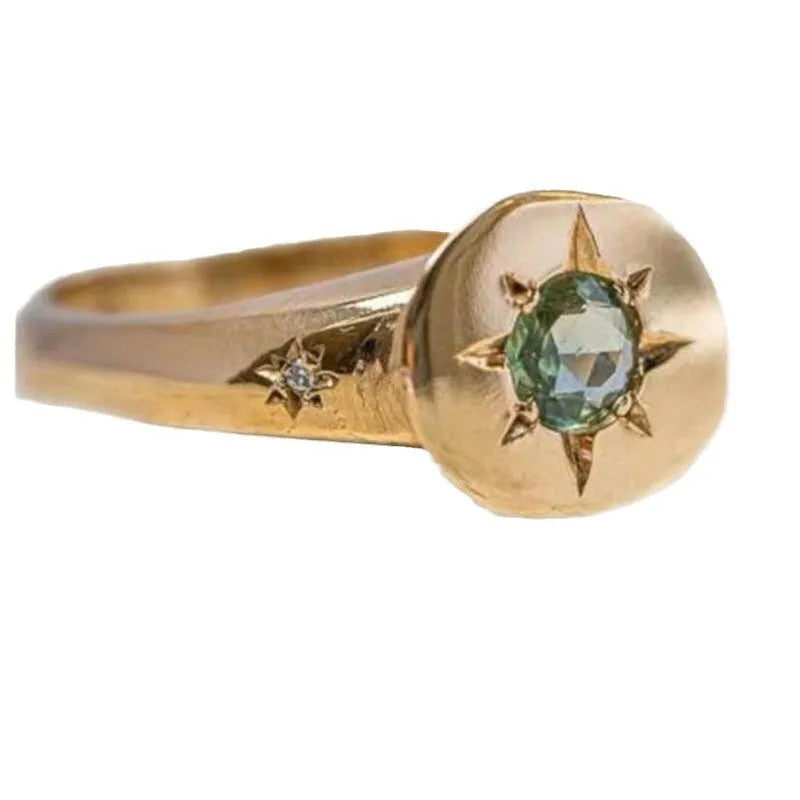 Gold coloured oval star zircon ring with adjustable opening on a plain background.