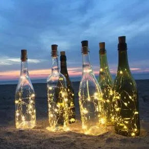 Silver wire LED string lights wrapped around wine bottle with warm white illumination