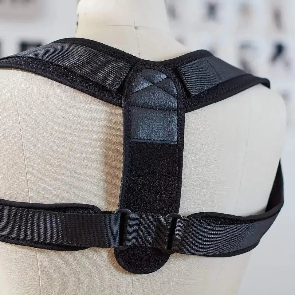 Black adjustable posture correction strap laid flat, showing its breathable material and adjustment mechanism.