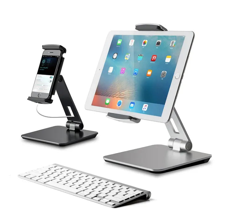 Folding aluminium and black plastic phone tablet stand on a desk, showing 360 degree rotation base.