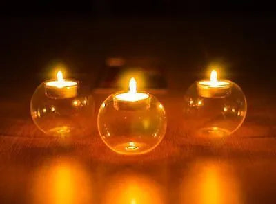 Handmade round hollow glass candle holder in three sizes on a wooden table.