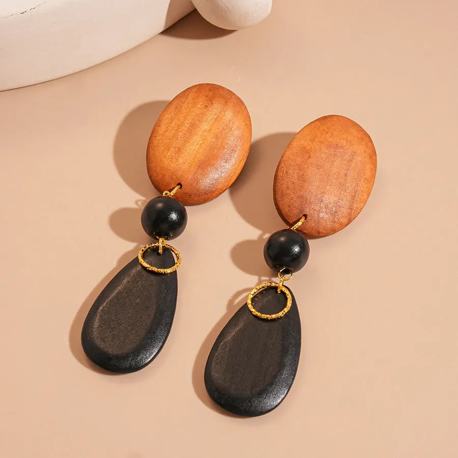 A pair of handcrafted wooden earrings with an elliptical shape in a silver, brown, and black colour finish.