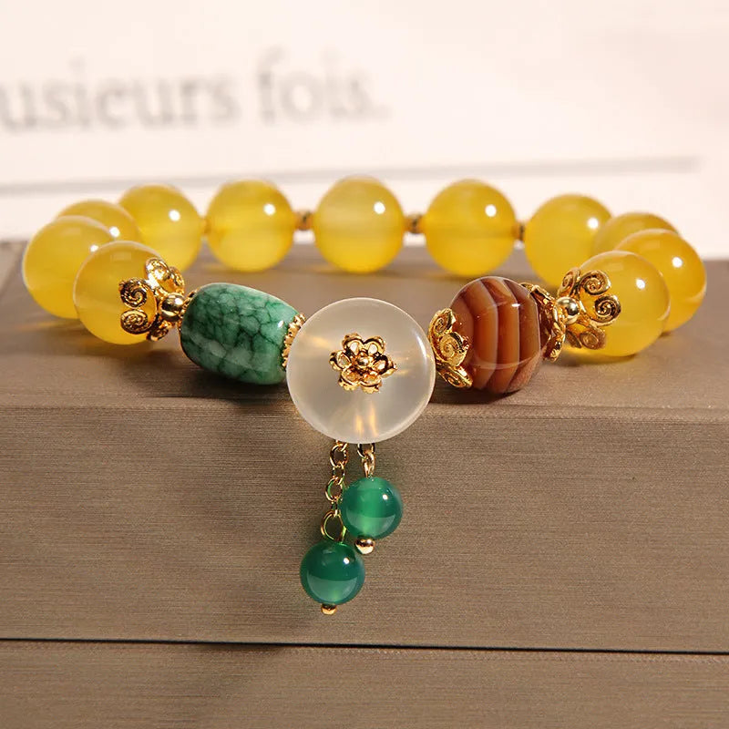 Close-up of a khaki yellow agate crystal bracelet with gold silk threading on a wrist.