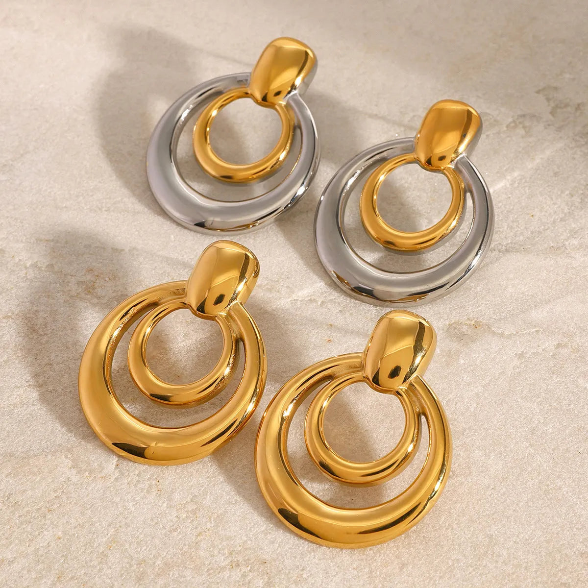 Round golden geometric hollow stud earrings made from titanium steel with an 18K gold electroplated finish.