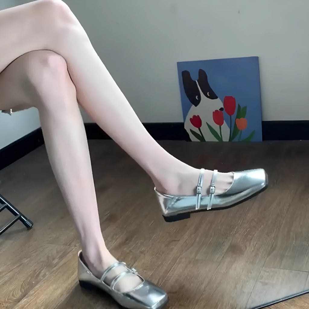 Women's silver leather ballet flats with a cross buckle strap, round toe, and low flat heel.