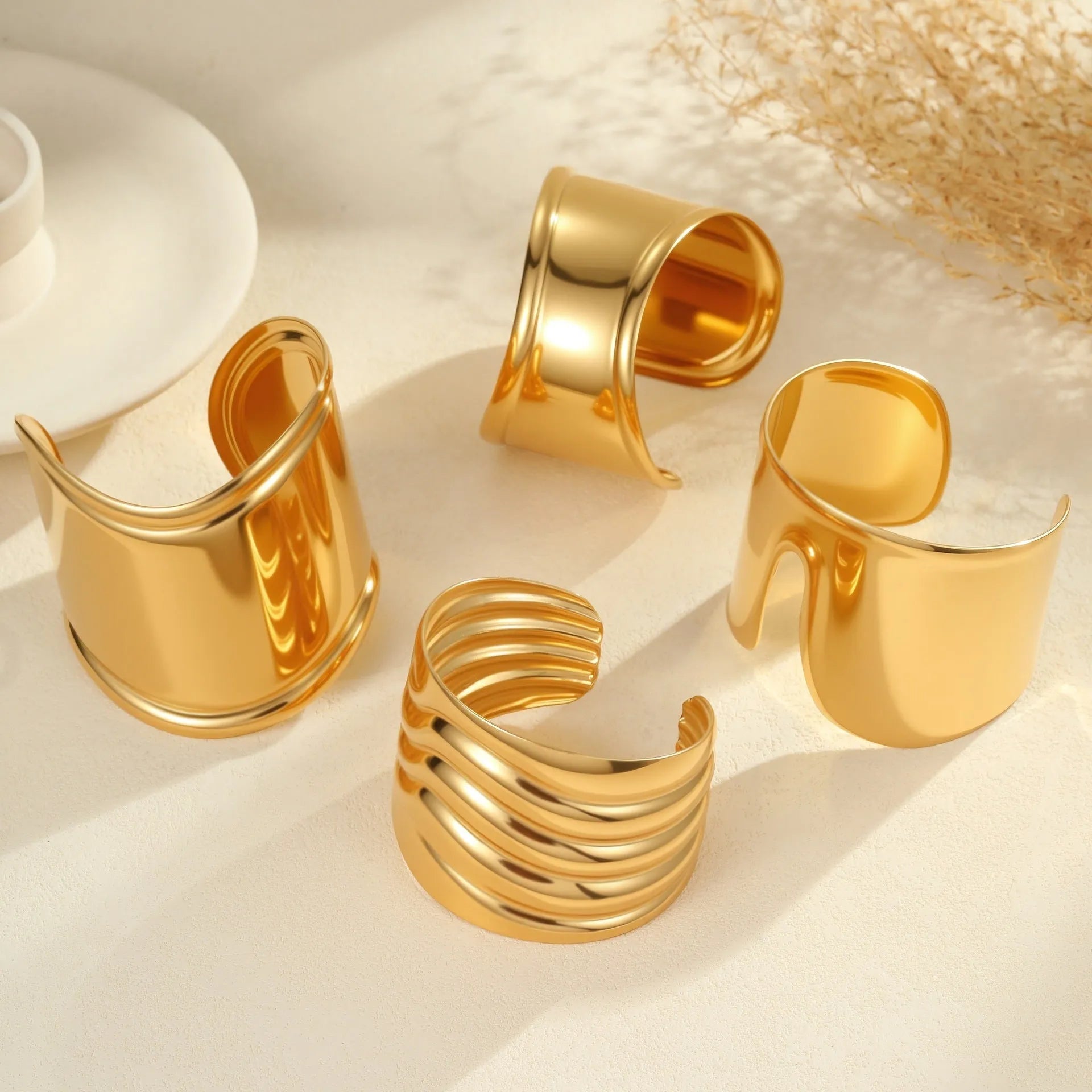 Wide geometric wave bracelet in gold-plated stainless steel on a woman's wrist.
