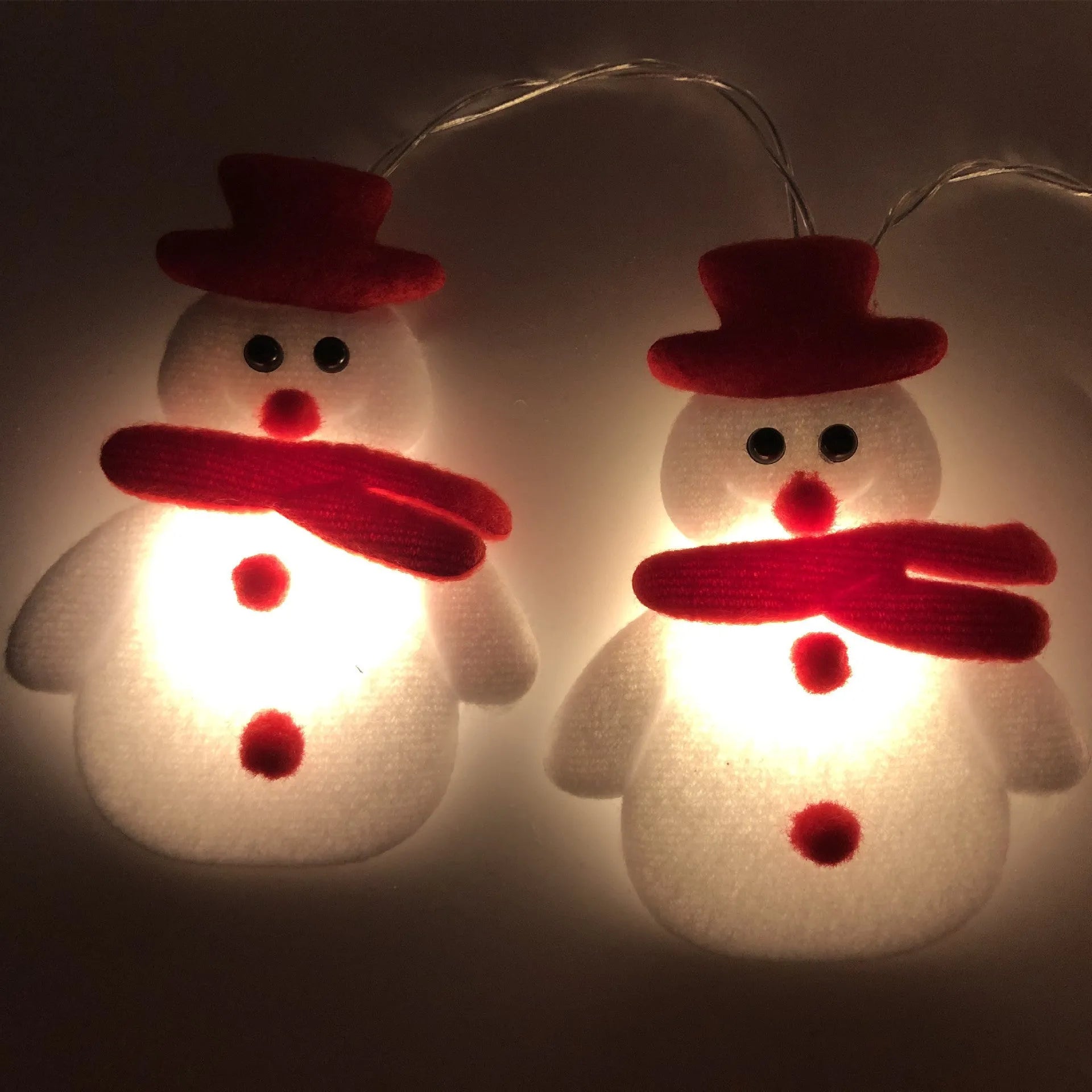 Christmas LED string lights with warm white glow showing snowman and elk deer themed lamps on a dark background
