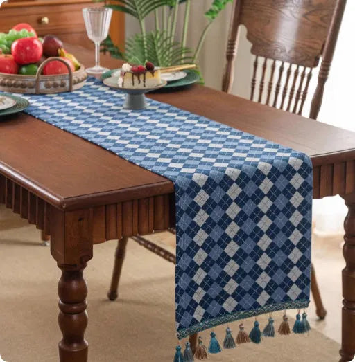 Long decorative table runner with tassels on a wooden dining table in a blue ginkgo leaf pattern.
