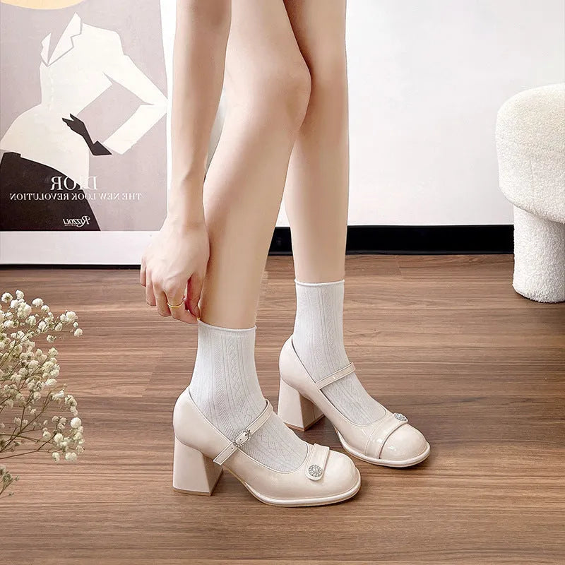 Women's black patent leather chunky heel shoes with round toe and buckle fastening on a white background.