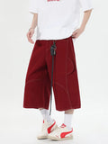 Women's retro denim shorts with multiple pockets in a wide-leg cropped style on a hanger.