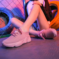 Women's white thick-soled woven trainers with front strap fastening on a plain background.
