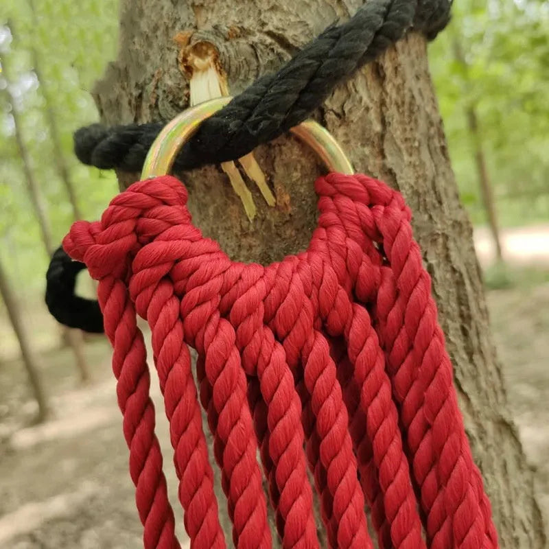 Nylon rope mesh outdoor hammock hung between two trees, showing its open weave and included tying ropes.