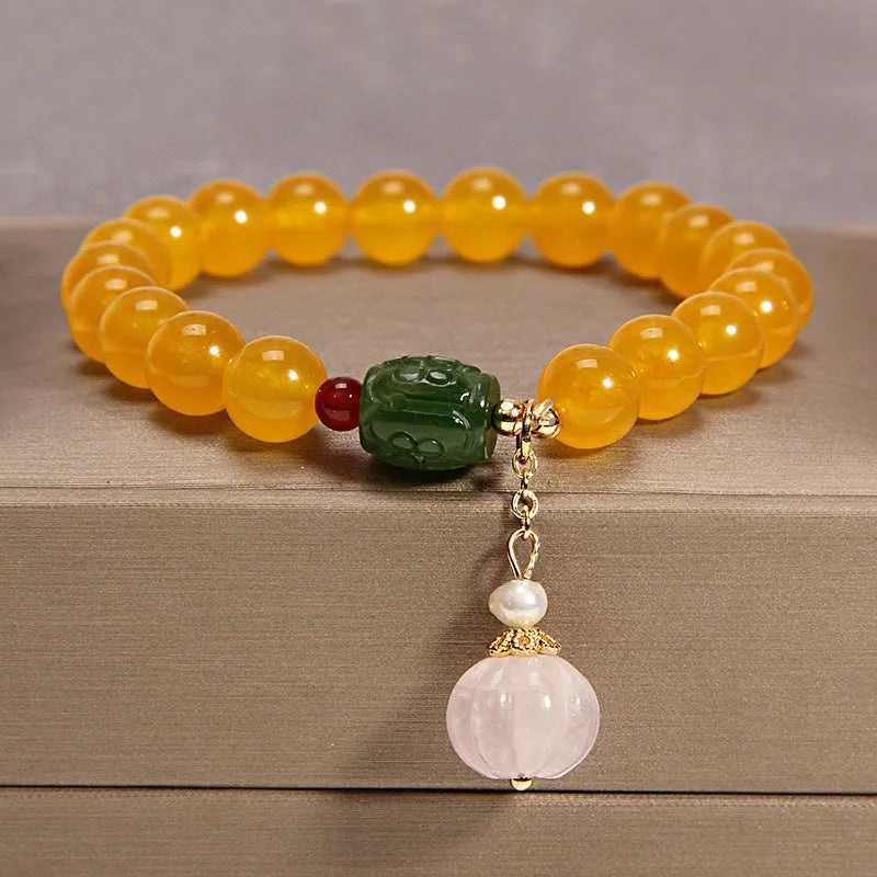 Close-up of a khaki yellow agate crystal bracelet with gold silk threading on a wrist.