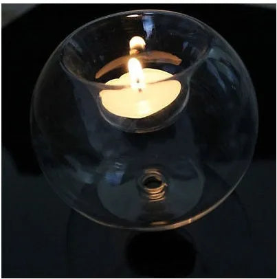 Handmade round hollow glass candle holder in three sizes on a wooden table.