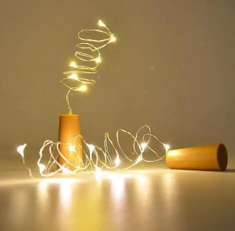 Silver wire LED string lights wrapped around wine bottle with warm white illumination