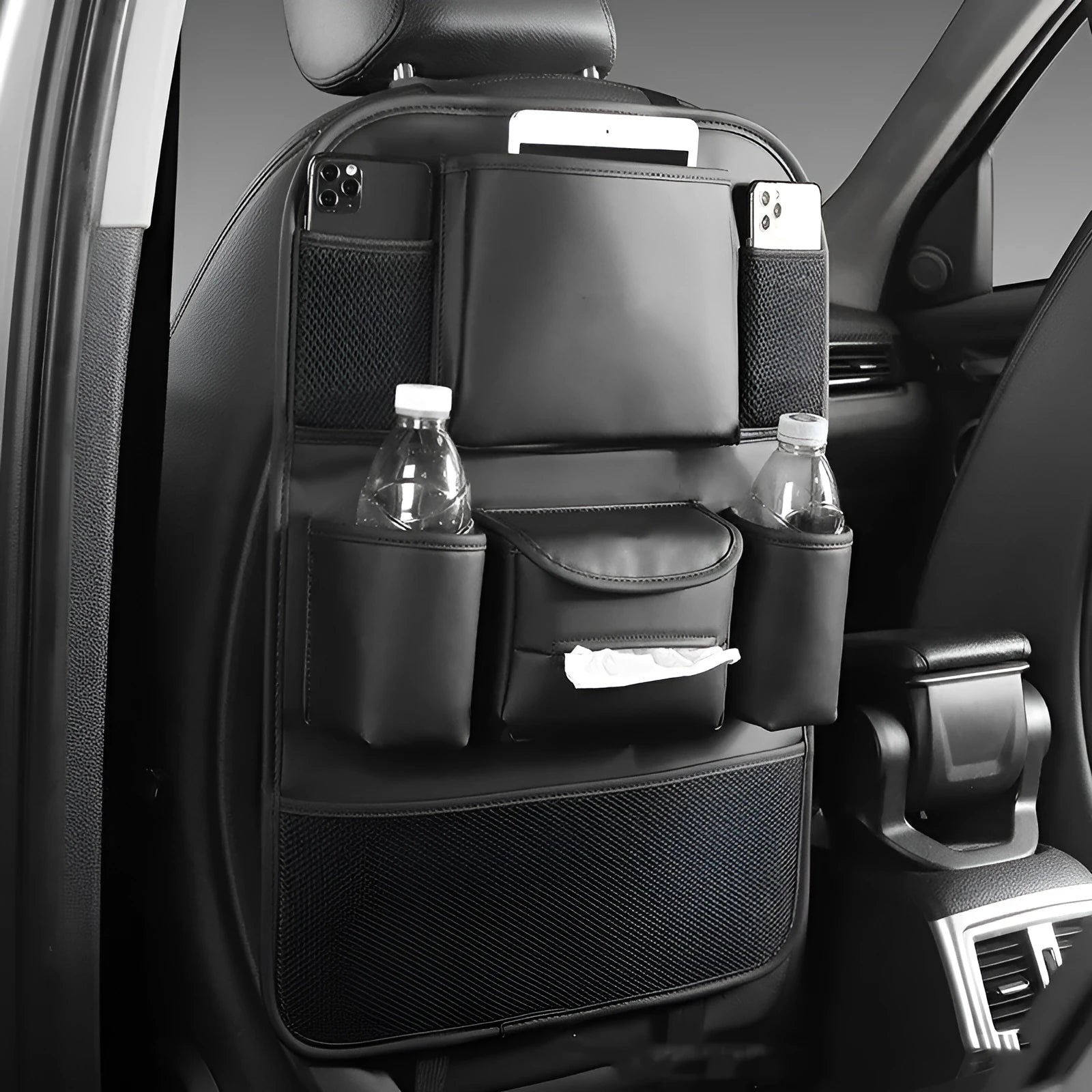 Black leather car seat back storage bag with pockets, shown suspended behind a car seat headrest.