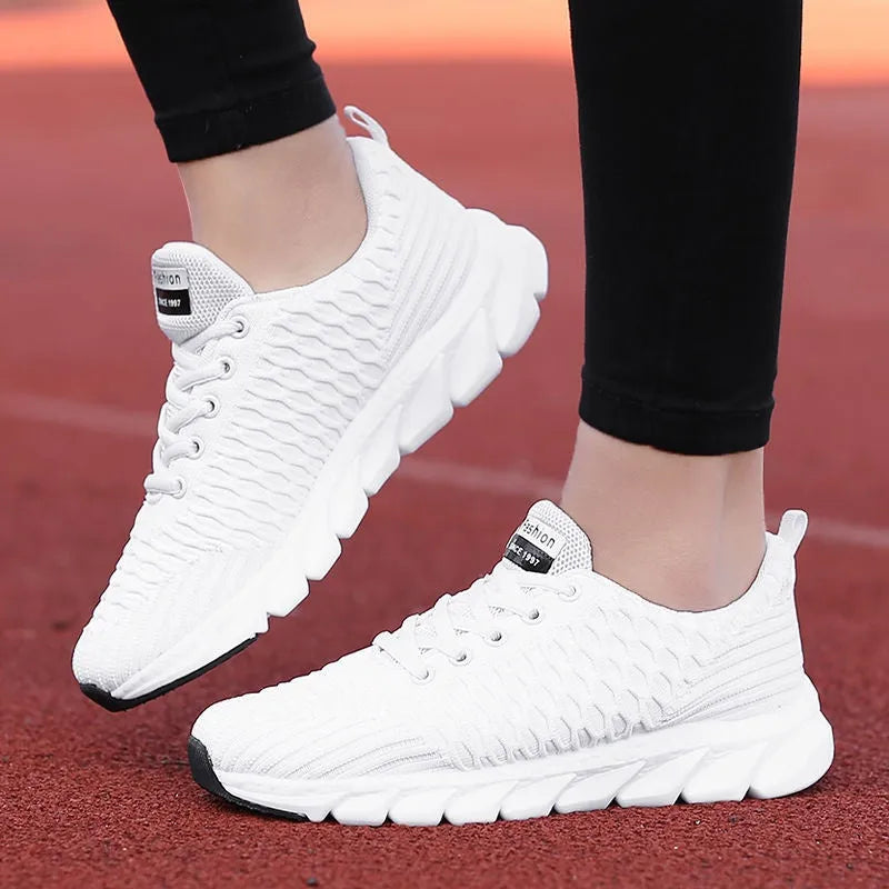 Women's running shoes with fly weave upper in black, pink, or white on a wear-resistant outsole.