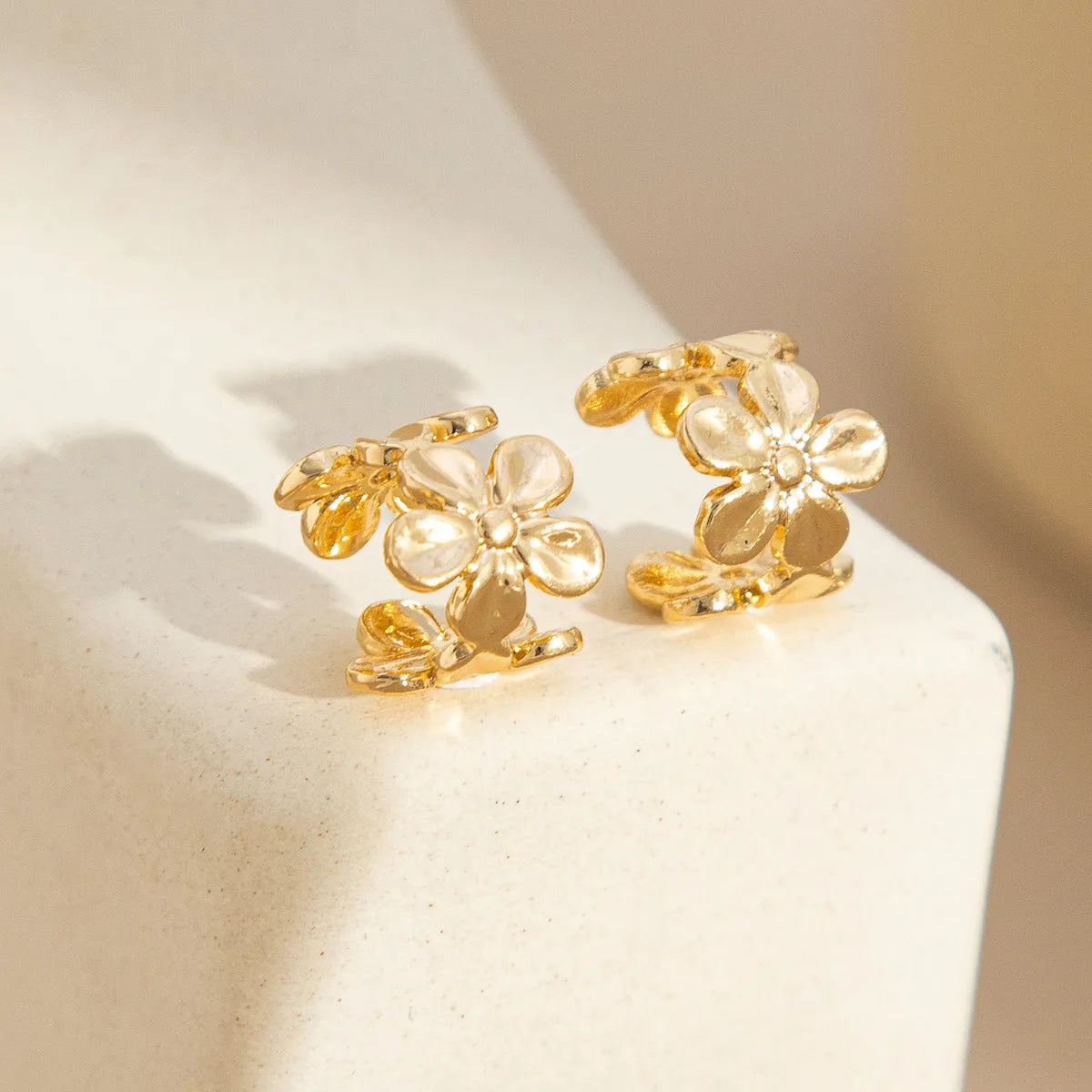 Women's gold starfish and conch shell drop earrings on white background