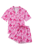 Pink women's pyjama set with bow print, featuring a top and trousers.