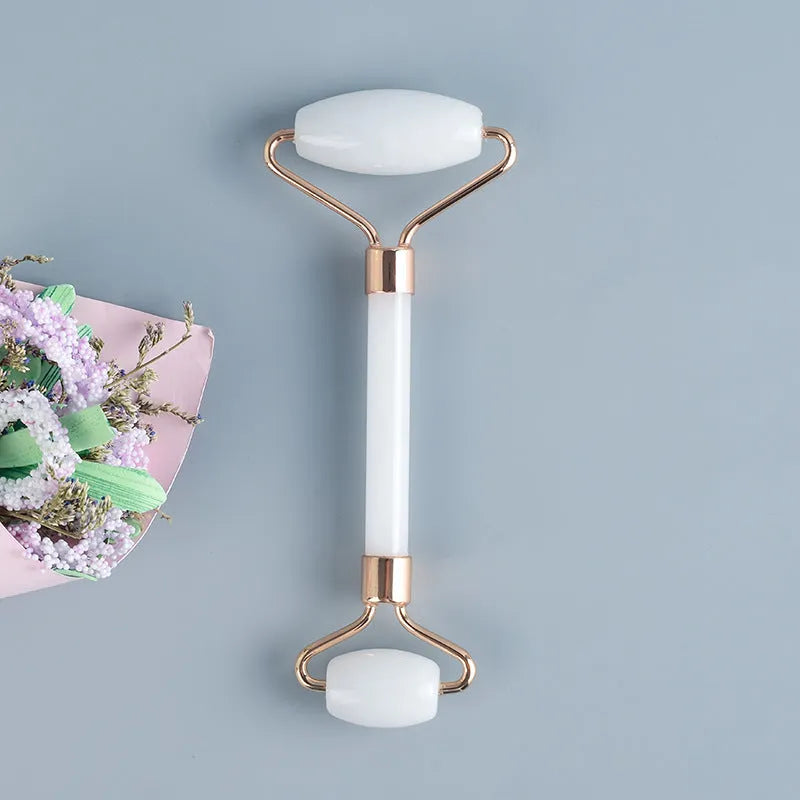 White jade double-headed facial roller and gua sha scraping board set on a storage tray.