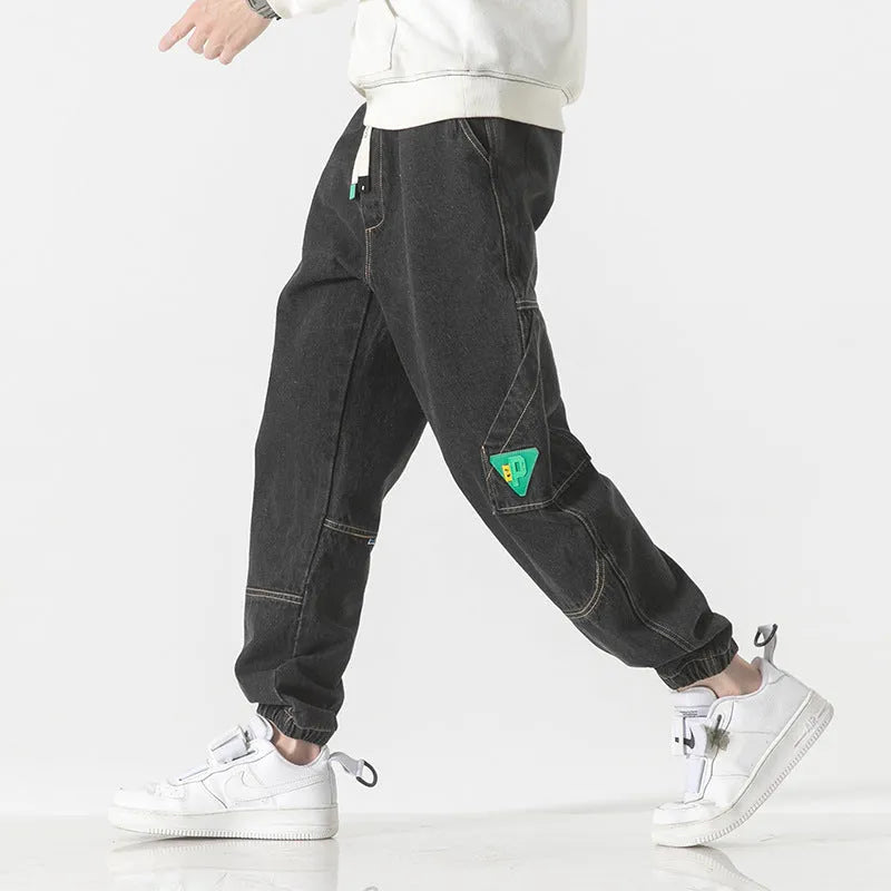 Men's loose-fit tapered cotton trousers in grey, showing the mid-waist and tapered leg cut.