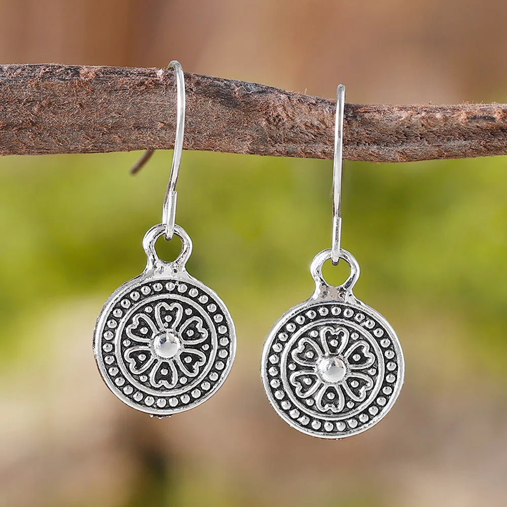 Close-up of a pair of women's geometric round bohemian retro style earrings with a distressed ethnic design in zinc alloy.
