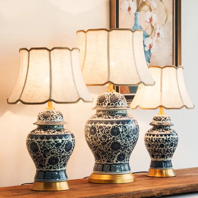 Blue and white porcelain Chinese table lamp with copper base and cloth shade on bedside table