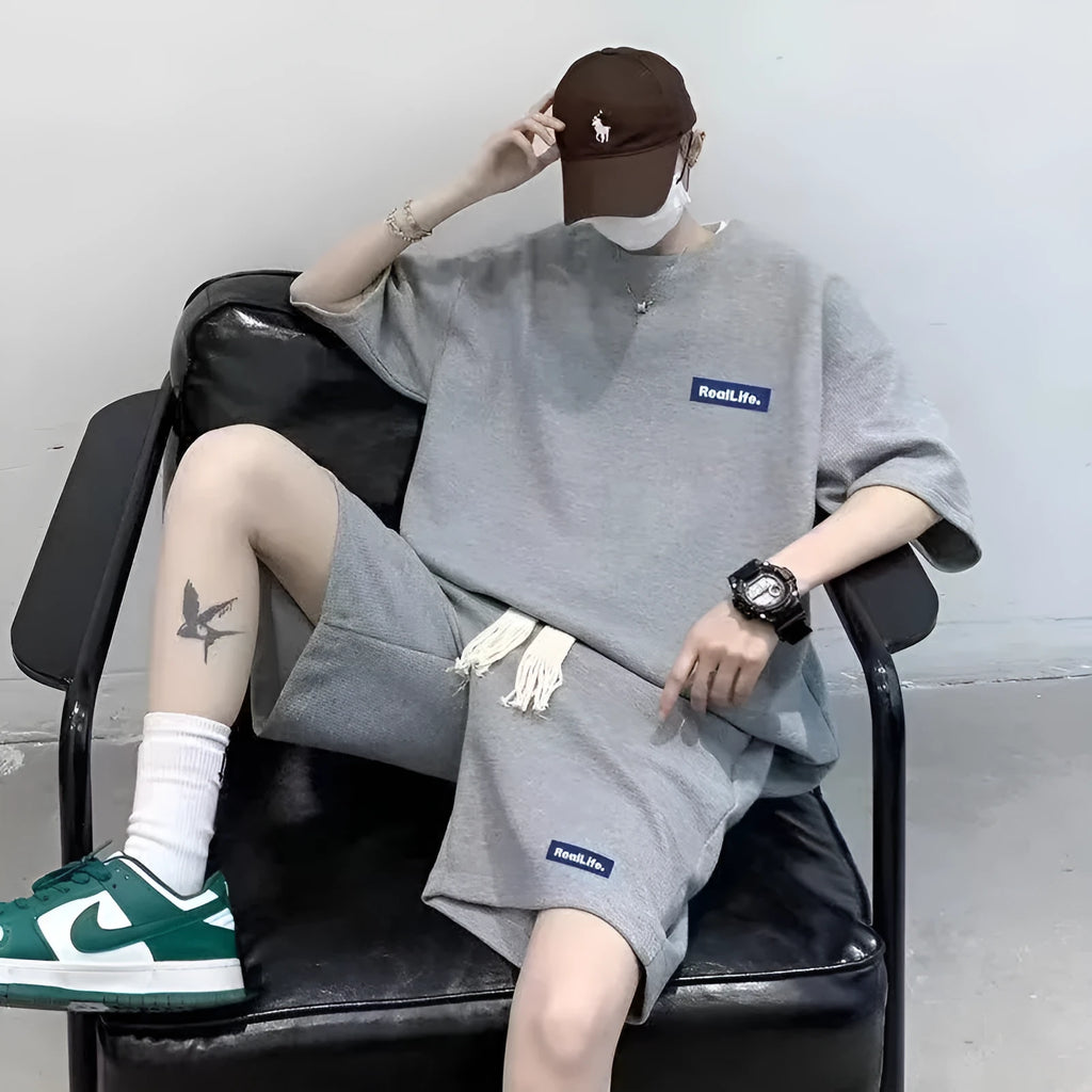 Man wearing a waffle-textured grey cotton short sleeve top and matching shorts from the leisure sport suit set.