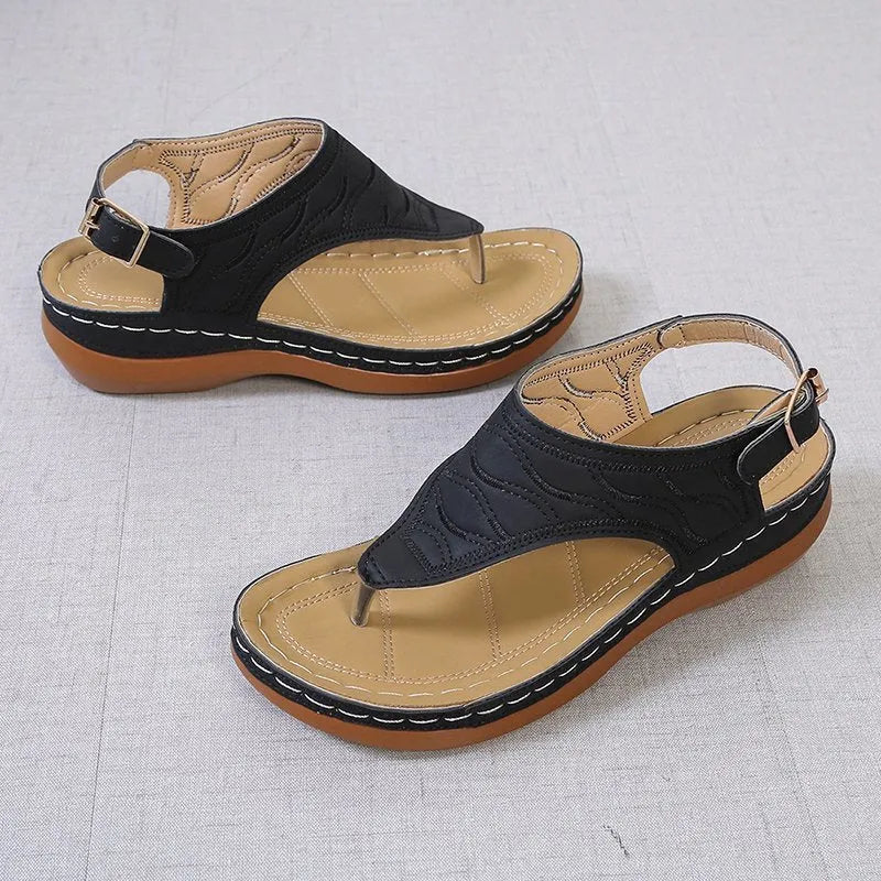 Women's black wedge heel sandals with an adjustable buckle strap on a light background.