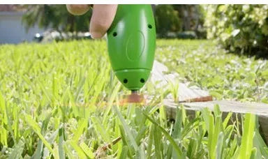 Cordless handheld zip trimmer with extension pole and debris shield on grass