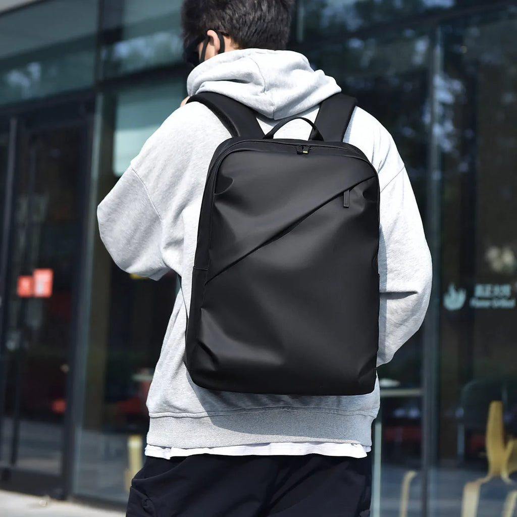 Large simple design waterproof backpack in grey with visible stitching, shown with a separate computer bag.
