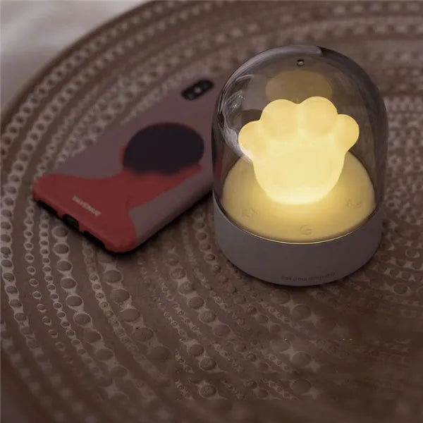 Grey or pink cat paw shaped USB rechargeable night light with music box on a desk.