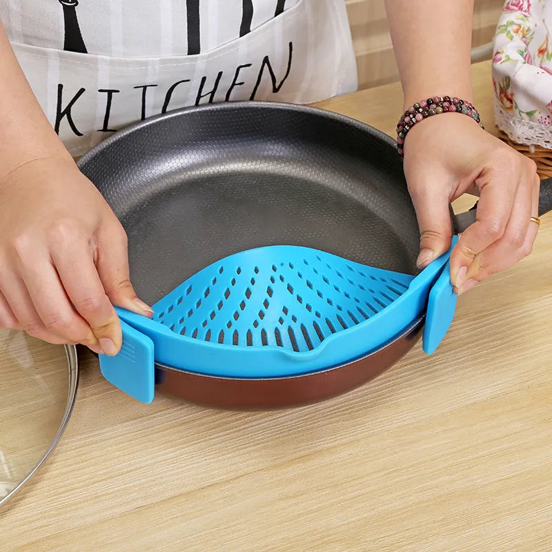 Silicone clip-on colander with stainless steel buckle attached to a pot, draining liquid, available in four colours.