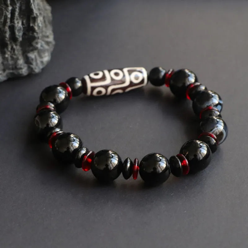 Hand-woven black agate Dzi bead bracelet on a wrist, showing geometric bead and woven band.