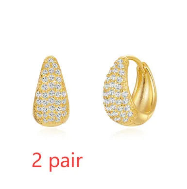 A pair of golden brass diamond-shaped earclip earrings with a round geometric design.