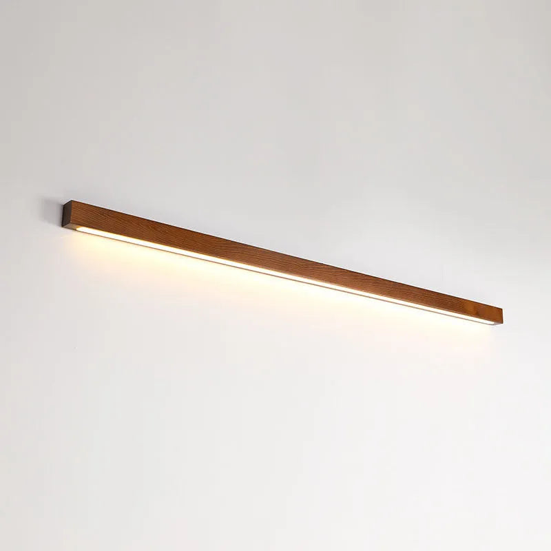 Slim walnut-colour wood and acrylic LED strip wall lamp in three length options on a white wall.