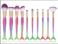 10 mermaid makeup brushes with multicolour nylon bristles and plastic handles laid flat
